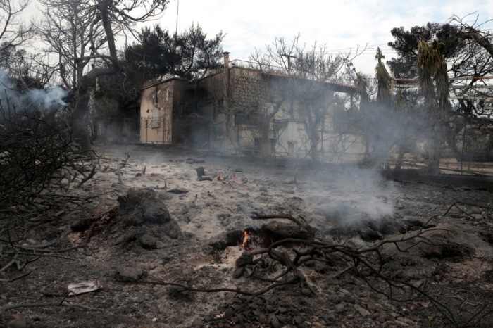 Blick auf ein schwelendes Feuer und ein verbranntes Haus (Hintergrund) in Argyra Akti, Mati. Foto: epa/Pantelis Saitas