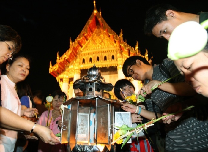 Mit Blumen und Kerzen in den Händen umrunden Buddhisten am Makha-Bucha-Tag dreimal den Tempel. Foto: epa/Narong Sangnak