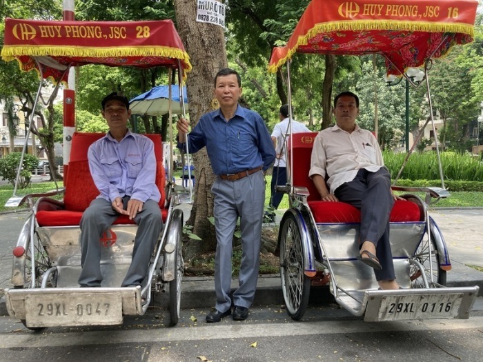 Cyclo-Fahrer Tran Viet Dac (l), der Chef der Betreiberfirma, Nguyen Huu Thu (M), und Nguyen Duc Manh, der ein Team von Fahrern betreut, stehen mit zwei Fahrradrikschas in der Altstadt von Hanoi. Foto: Carola Frentzen/dpa