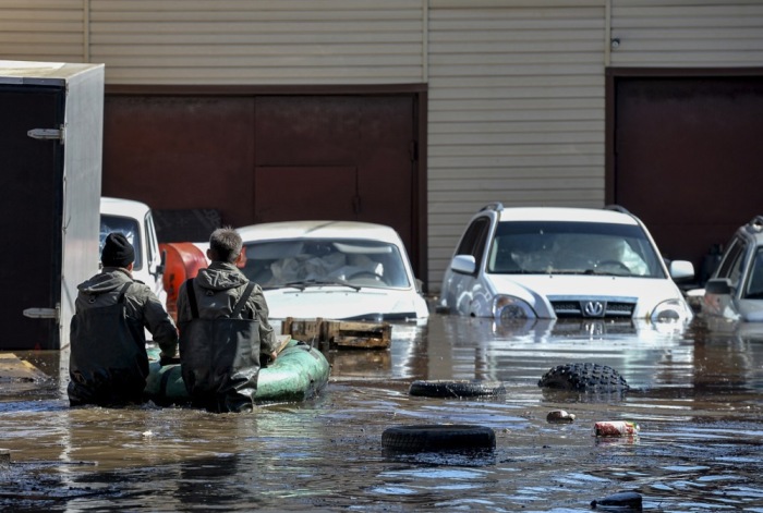 Anwohner inspizieren ihr Auto in einem überfluteten Wohngebiet in Orenburg. Foto: EPA-EFE/Stringer