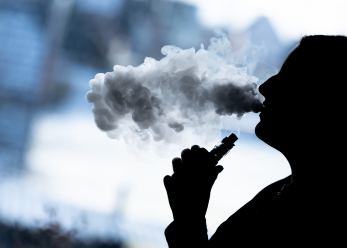 Eine junge Frau raucht in ihrer Wohnung mit einer E-Shisha und ist dabei als Silhouette zu sehen. Eine Mehrheit der Deutschen wünscht sich laut einer Umfrage ein härteres Vorgehen gegen E-Zigaretten und Tabak-Erhitzer. Foto: Silas Stein/dpa