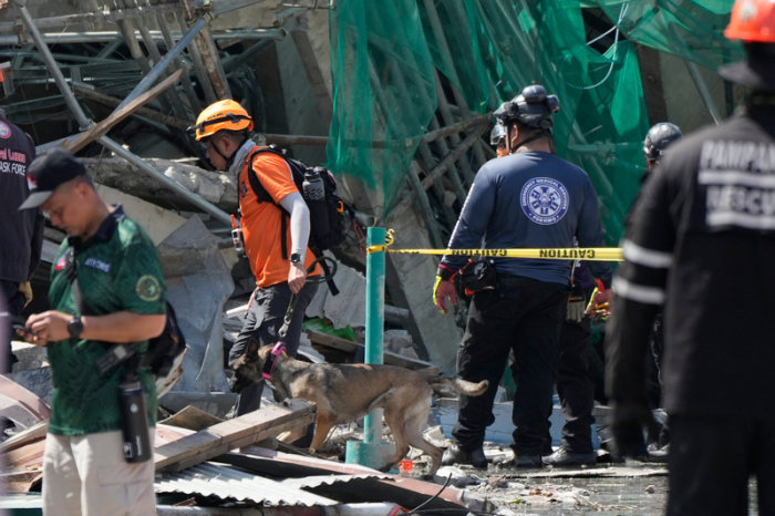 Retter setzen einen K9-Hund an einem eingestürzten Gebäude ein, in dem Dutzende von Menschen in der Stadt Angeles in der Provinz Pampanga eingeschlossen sein sollen. Foto: Aaron Favila/Ap/dpa