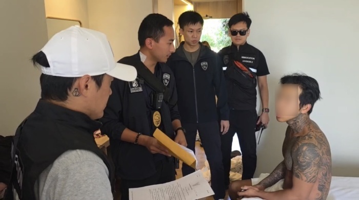 Ermittler der Einwanderungsbehörde eröffnen dem südkoreanischen Verdächtigen den Durchsuchungsbeschluss in seiner Wohnung in Pattaya. Bild: TMN.TV