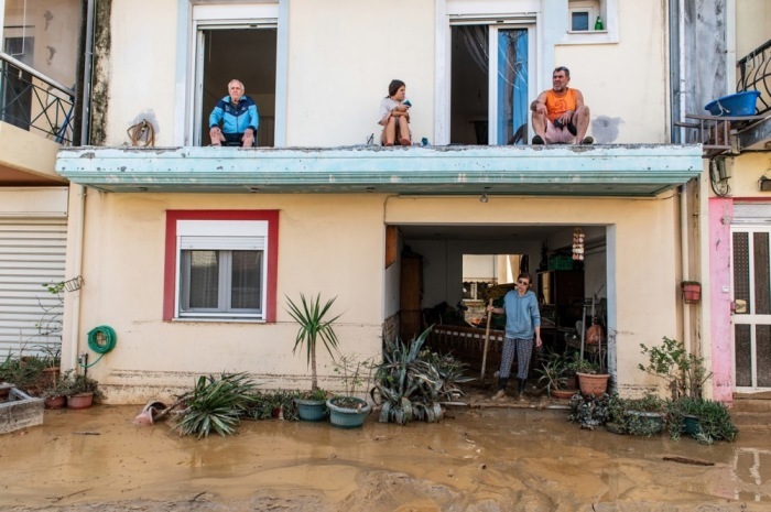 Anwohner beobachten, wie eine Frau mit einer Schaufel versucht, das Wasser und den Schlamm um ihr Grundstück in der Hafenstadt Volos zu entfernen. Foto: epa/Hatzipolitis Nicolaos
