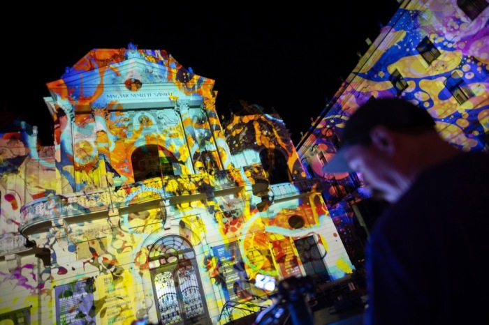 Ein Besucher betrachtet Steve Pavlovskys «Liquid Light Show» auf dem Theaterplatz beim Zsolnay-Lichtfestival in Pécs, Ungarn. Symbolfoto: epa/Judit Ruprech
