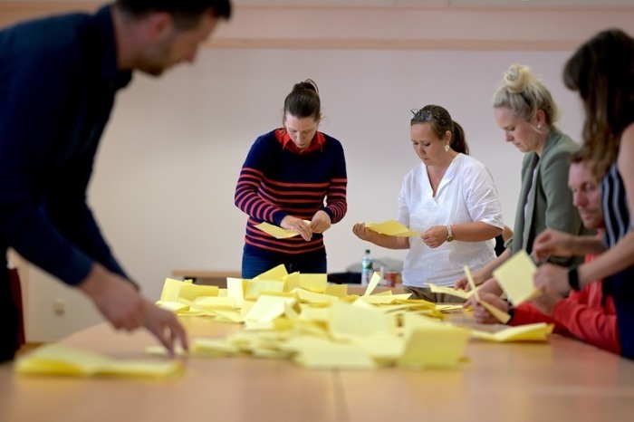 Wahlhelfer sortieren die Stimmzettel für die Auszählung der Stimmen zur Bürgermeisterwahl in Arnstadt im Wahllokal in der Stadthalle Arnstadt. Foto: Jacob Schröter/dpa