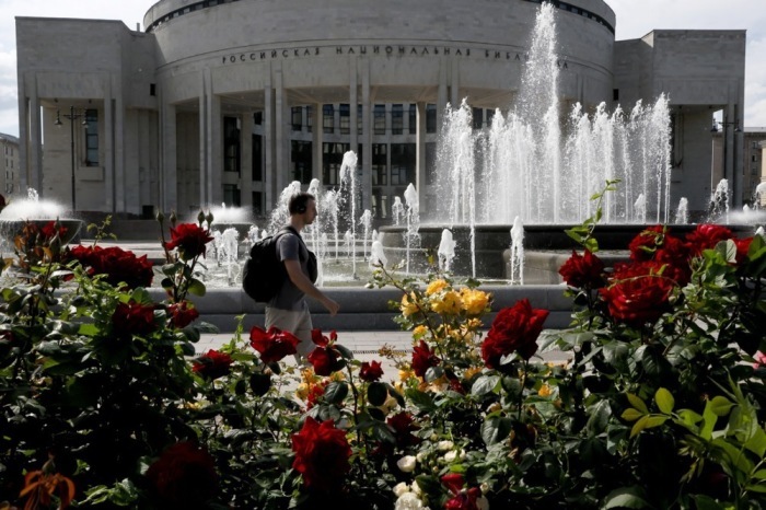 Ein Mann geht an einem Springbrunnen vor der Russischen Nationalbibliothek in St. Petersburg vorbei. Foto: EPA/Anatoly Maltsev
