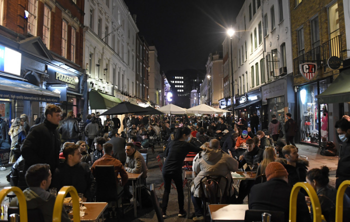 Menschen essen und trinken in der Old Compton Street im Stadtteil Soho im Zentrum von London. Foto: Alberto Pezzali/Ap/dpa