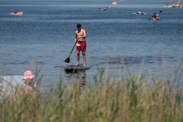 Ein Mann fährt bei großer Hitze mit einem Paddleboard über den Piaseczno-See in Ostpolen. Foto: EPA/Wojtek Jargilo