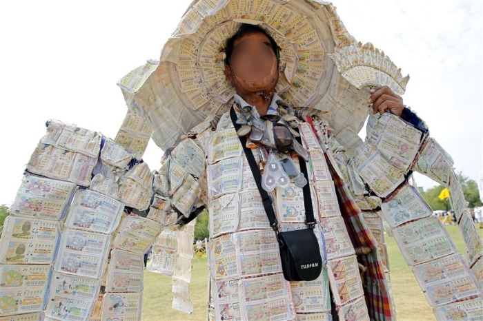 Thailändischer Lottosüchtiger, trägt seine Kleidung mit Tausenden von Lottoscheinen verziert. Foto: EPA/Rungroj Yongrit