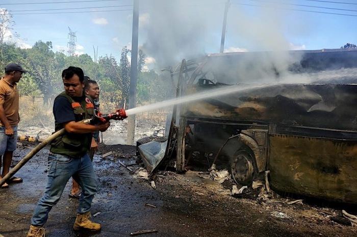 Rettungskräfte löschen den ausgebrannten Reisebus nach einem schweren Unfall in Süd-Sumatra mit zahlreichen Todesopfern. Foto: epa/Bpbd Muratara/handout