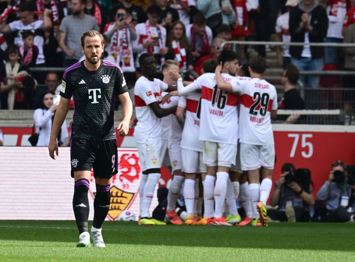 Münchens Harry Kane (l) geht nach dem 1:0 über den Platz. Im Hintergrund jubeln die Spieler des VfB Stuttgart. Foto: Bernd Weißbrod/dpa