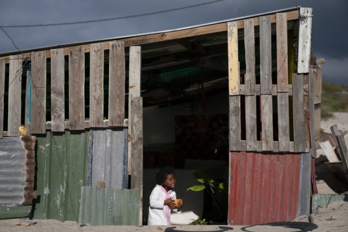 Ein Mädchen verlässt in Kapstadt mit einer Schüssel Brei ihre Hütte. Das Hilfsprogramm des 9 Miles Project versorgte während der Corona-Pandemie bedürftige Familien mit Nahrung. Foto: Nic Bothma/epa/dpa.