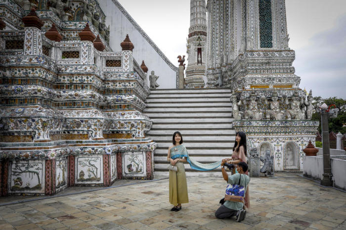 Touristen posieren – gekleidet in traditionellen Kostümen – für ein Foto im Wat Arun am Ufer des Chao-Phraya-Flusses in Bangkok. Foto: epa/Diego Azubel