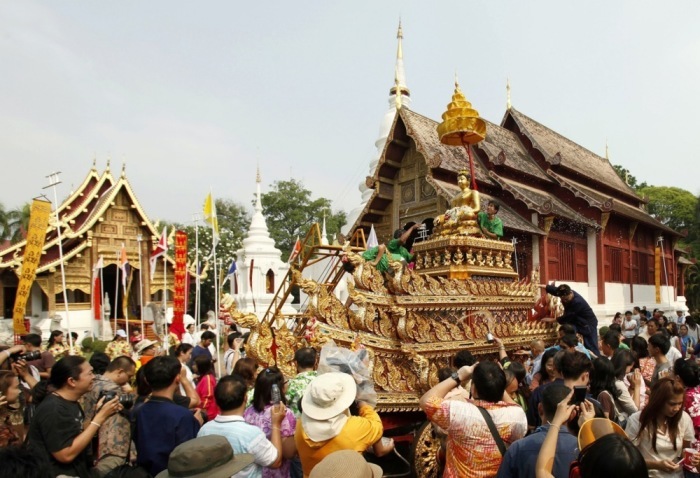 Besucher verfolgen in Chiang Mai eine traditionelle Songkran-Prozession mit geschmückter Buddha-Figur vor Tempelkulisse. Foto: epa/Pongmanat Tasiri