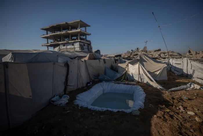 Vertriebene Palästinenser nutzen an einem heißen Sommertag in einem Zeltlager im Osten von Gaza-Stadt ein provisorisches Wasserbecken zur Abkühlung. Foto: EPA/Mohammed Saber