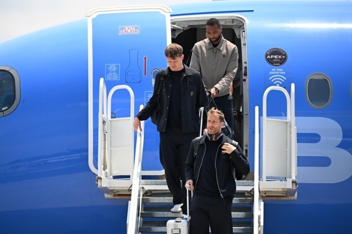 Jonathan Tah, Torhüter Alexander Nübel und Torhüter Oliver Baumann verlassen das Flugzeug nach der Ankunft am Flughafen Smith Reynolds. Foto: Federico Gambarini/dpa