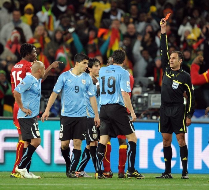 WM 2010, Viertelfinale, Uruguay - Ghana, Schiedsrichter Olegario Benquerenca (r) stellt Uruguays Luis Suarez (3vl) nach einem Handspiel vom Platz. Foto: Georgi Licovski