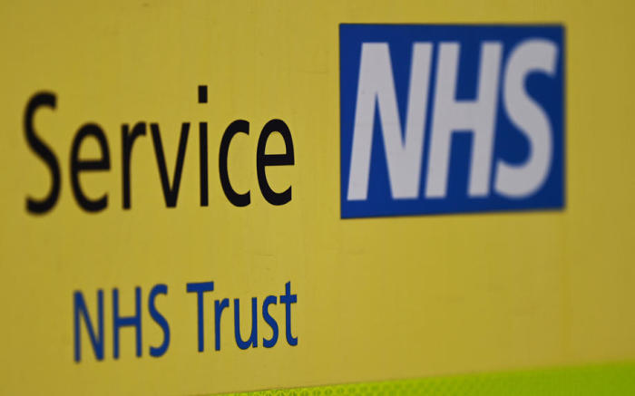 NHS Trust-Branding vor einem NHS-Krankenhaus in London. Foto: epa/Andy Rain