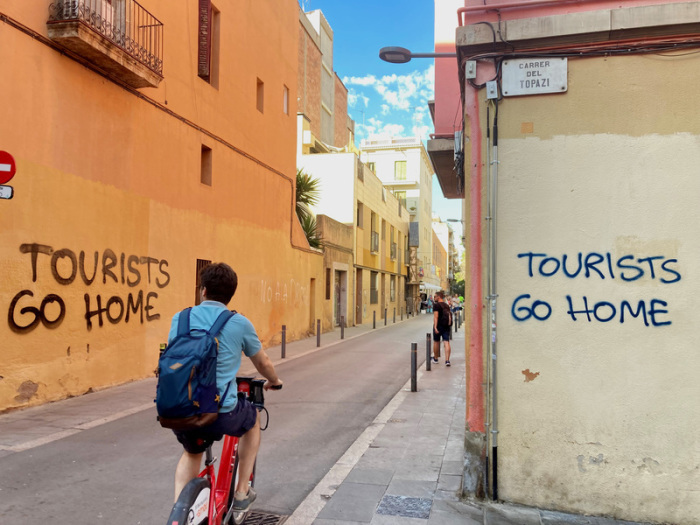 Ein an eine Wand im Künstlerviertel Vila de Gràcia gesprühter Schriftzug «Tourists Go Home». Foto: Emilio Rappold/dpa