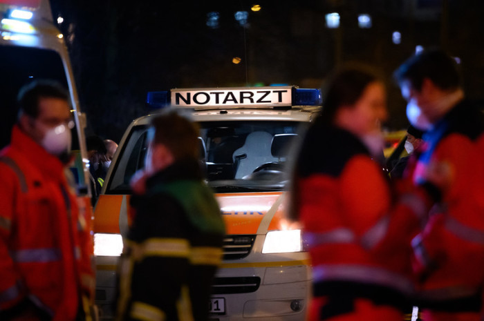«Notarzt» steht auf einem Fahrzeug der Feuerwehr, vor dem sich mehrere Einsatz- und Rettungskräfte besprechen. Foto: Jonas Walzberg/dpa