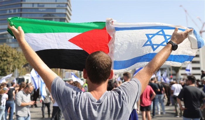 Ein Mann hält die israelische und die palästinensische Flagge hoch, als Demonstranten während einer Anti-Regierungs-Demonstration in Tel Aviv die Ayalon Road im Zentrum blockieren. Foto: epa/Abir Sultan