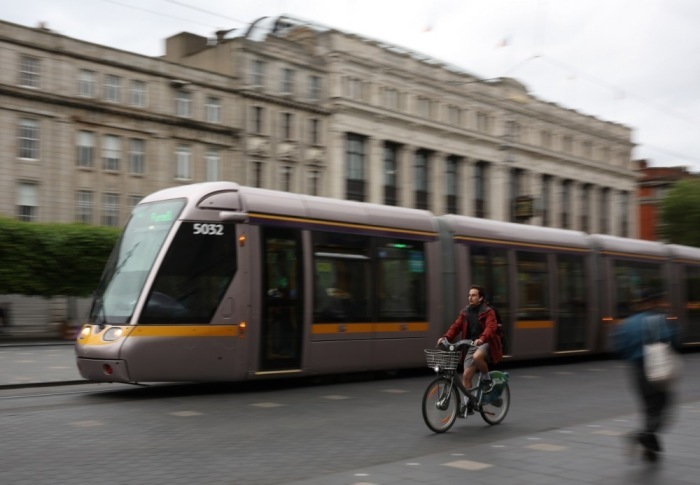 Eine Radfahrerin überholt eine Dubliner Luas Tram in Dublin. Foto: epa/Adam Vaughan