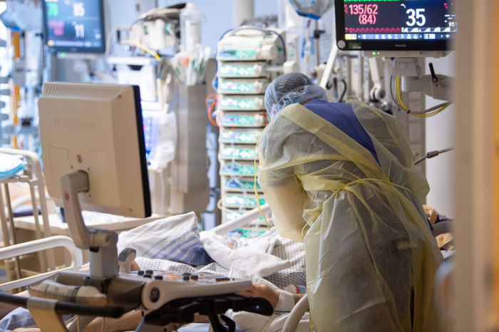 Ein Intensivpfleger steht auf der Intensivstation eines Krankenhauses neben einem Covid-19-Patienten. Foto: Sebastian Gollnow/dpa