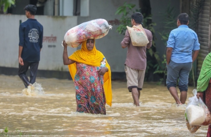 Die Leute waten durch das Hochwasser in einem vom Hochwasser betroffenen Gebiet in Burichong, Bezirk Comilla. Foto: epa/Monirul Alam