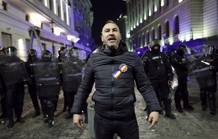 Ein alleinstehender Anhänger von Calin Georgescu (C) ruft seinen Mitstreitern zu, während er mit dem Rücken zu den Bereitschaftspolizisten steht. Foto: epa/Robert Ghement