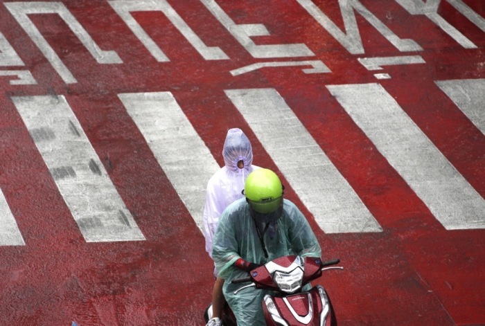 Ein Motorrollerfahrer und sein Sozius fahren bei Regen über eine Straße in Bangkok. Für Donnerstag werden in der Hauptstadt vor allem am Nachmittag und Abend weitere Schauer und Gewitter erwartet. Foto: epa/Rungroj Yongrit