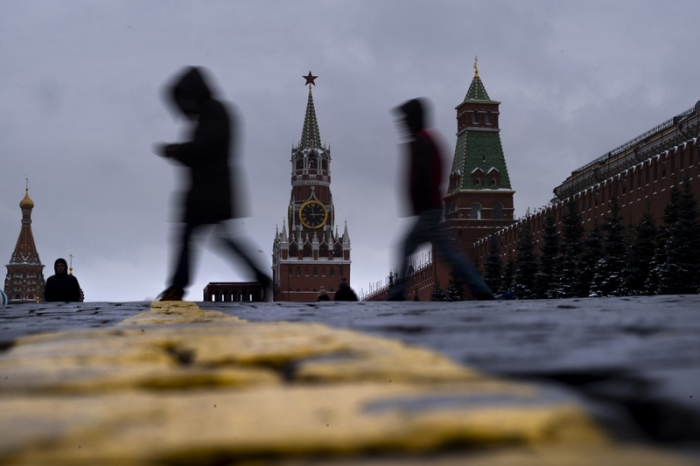 Menschen gehen vor dem Erlöserturm im Kreml (M) über den Roten Platz. Foto: Alexander Zemlianichenko/Ap/dpa