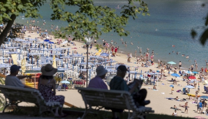 Menschen suchen im Schatten nahe dem Strand La Concha in San Sebastián Schutz vor der anhaltenden Hitzewelle in Spanien. Foto: EPA/Javier Etxezarreta