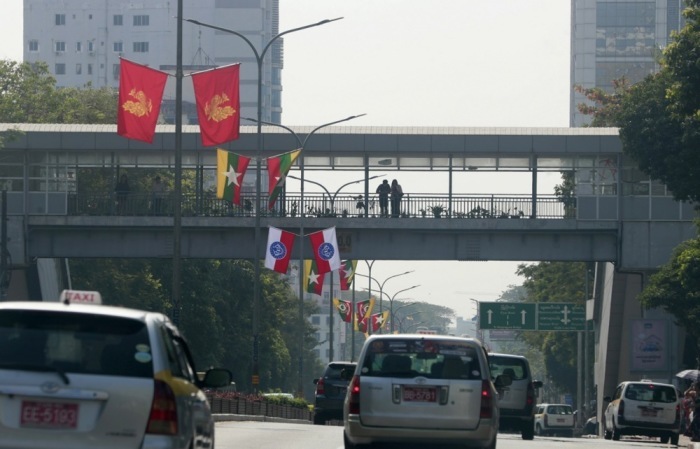 Fahrzeuge passieren eine Straße in Yangon, während Menschen am fünften Jahrestag des Militärputsches auf einer Fußgängerbrücke stehen. Foto: epa/Nyein Chan Naing