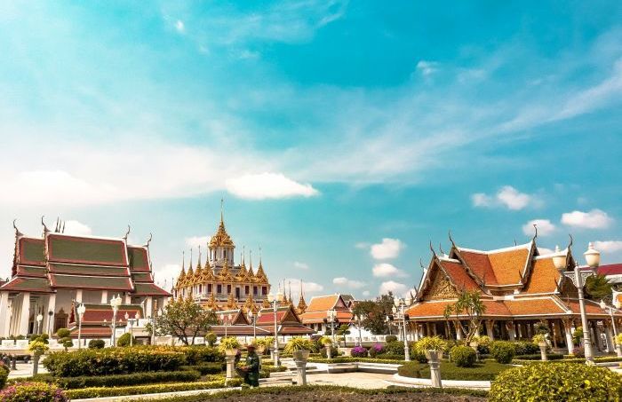 Der prachtvolle Loha Prasat in Bangkok erstrahlt mit seinen goldenen Spitzen unter einem strahlend blauen Himmel inmitten gepflegter Gartenanlagen. Foto: Unsplash/Alejandro Cartagena