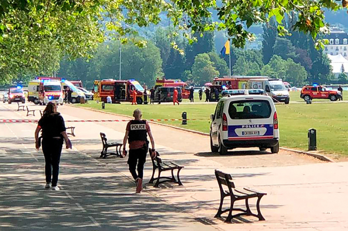 Polizisten und Rettungskräfte gehen nach einem Messerangriff in einem Park zum Tatort. Foto: Florent Pecchio/L'essor Savoyard/ap/dpa