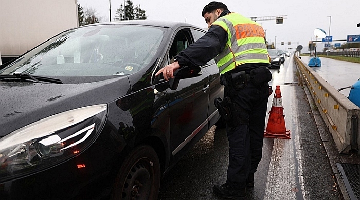 Ein deutscher Polizist stoppt ein Auto an einem Grenzübergang. Foto: EPA-EFE/Anna Szilagyi