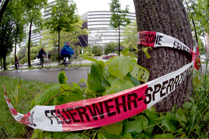Rot-weißes Absperrband der Feuerwehr hängt an einem Baum vor dem Europäischen Patentamt (im Hintergrund). Foto: picture alliance/dpa