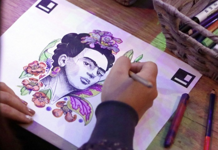 Besucherin koloriert ein Porträt von Frida Kahlo in einer immersiven Ausstellung in Bogotá, die Leben und Werk der mexikanischen Künstlerin erlebbar macht Foto: EPA/Carlos Ortega