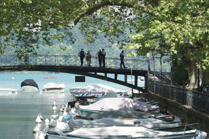 Polizeibeamte stehen auf einer Brücke in der Nähe des Tatorts nach einer Messerattacke am in den französischen Alpen. Foto: Laurent Cipriani/Ap/dpa