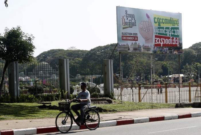Ein Mann fährt in Yangon an einem Wahlplakat vorbei. Aktivisten rufen zu einem landesweiten «stillen Streik» gegen die Wahlpläne der Militärjunta auf. Foto: epa/Nyein Chan Naing