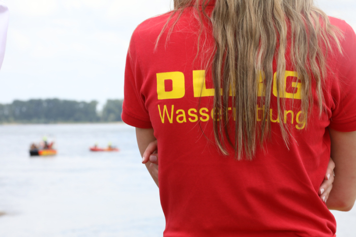 Ein Mitglied der Deutschen-Lebens-Rettungs-Gesellschaft (DLRG) beobachtet eine Rettungsübung auf dem Rhein. Foto: Sascha Thelen/dpa
