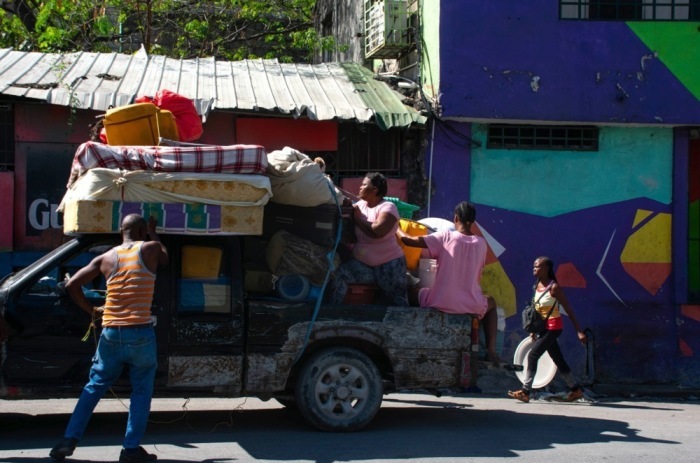 Einwohner verlassen ihre Häuser mit ihren Habseligkeiten in der Nähe des haitianischen Nationalgefängnisses nach dem Angriff bewaffneter Banden gestern Abend in Port-au-Prince. Foto: epa/Siffroy Clarens