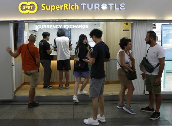 Kunden wechseln Geld an einem Schalter von SuperRich in Bangkok. Die starke Aufwertung des Baht beeinflusst derzeit die Wechselkurse und das Geschäft der Devisenhändler. Foto: epa/Rungroj Yongrit