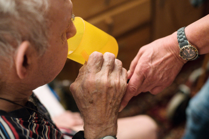 ine ambulante Pflegerin hilft einem alten Mann bei der Tabletteneinnahme. Der alte Mann trinkt Wasser. Foto: Jana Bauch/dpa