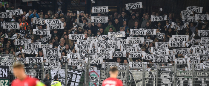 Fans von Wolfsburg protestieren mit Plakaten gegen die Zerstückelung der Spieltage. Foto: Patrick Seeger/dpa
