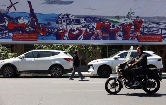 Passanten gehen in Teheran an einem antiamerikanischen Plakat nahe der ehemaligen US-Botschaft vorbei Foto: EPA/Abedin Taherkenareh