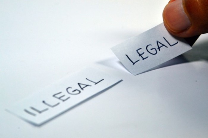 Zwei Zettel. Einer mit der Aufschrift Illegal. Der andere mit der Aufschrift legal wird zwischen Daumen und Zeigefinger gehalten. Bildquelle: Ramdlon / pixahive.com