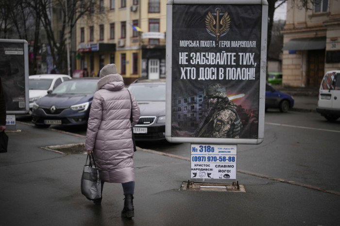 Eine Frau geht an einem Transparent mit der Aufschrift «Marineinfanteristen - Helden von Mariupol - vergesst nicht die, die noch in Gefangenschaft sind» vorbei. Foto: Daniel Cole/Ap/dpa