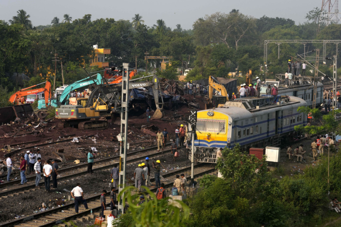 Menschen beobachten die Stelle, an der die Züge im Bezirk Balasore im ostindischen Bundesstaat Orissa entgleist sind. Foto: Rafiq Maqbool/Ap
